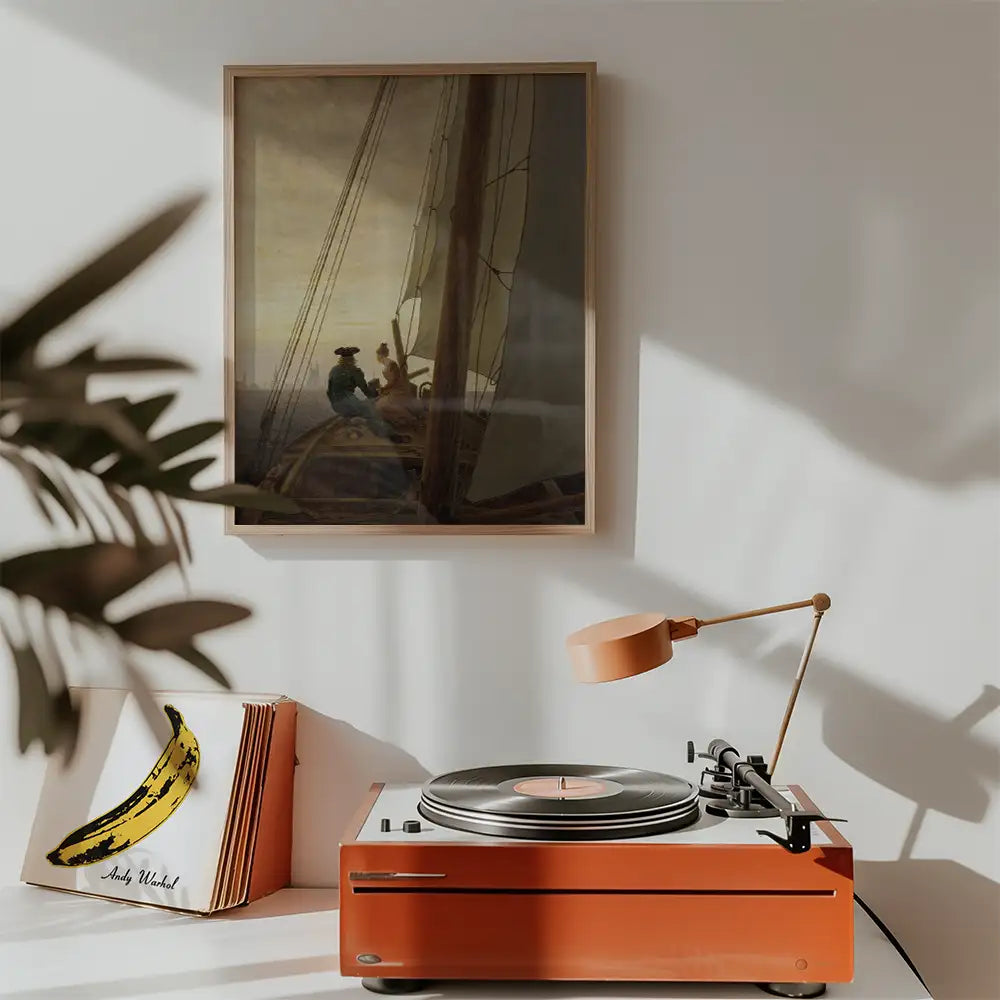 Painting of two people on a boat framed on the wall above a vintage record player and an album cover featuring a banana illustration.