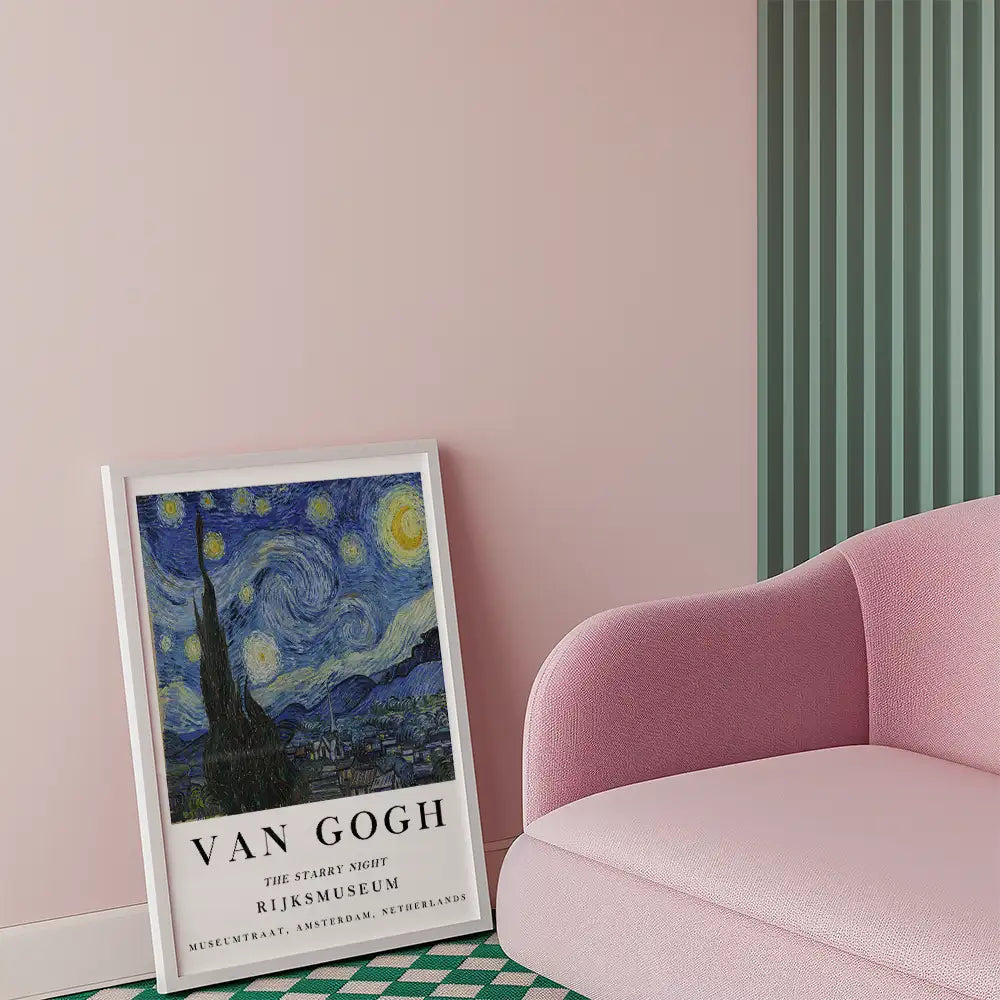 Framed replica of Vincent van Gogh's "The Starry Night" artwork leaning against a wall beside a pink sofa.