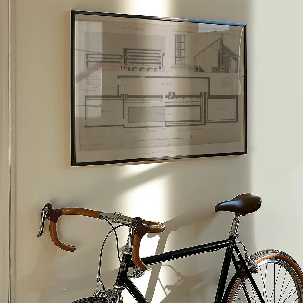 Framed architectural blueprint artwork hanging on a wall beside a vintage black bicycle.