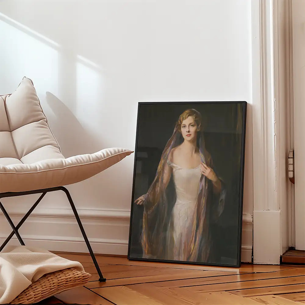 Framed portrait painting of a woman in a white dress with a colorful shawl, displayed next to a modern chair in a well-lit, minimalist room.