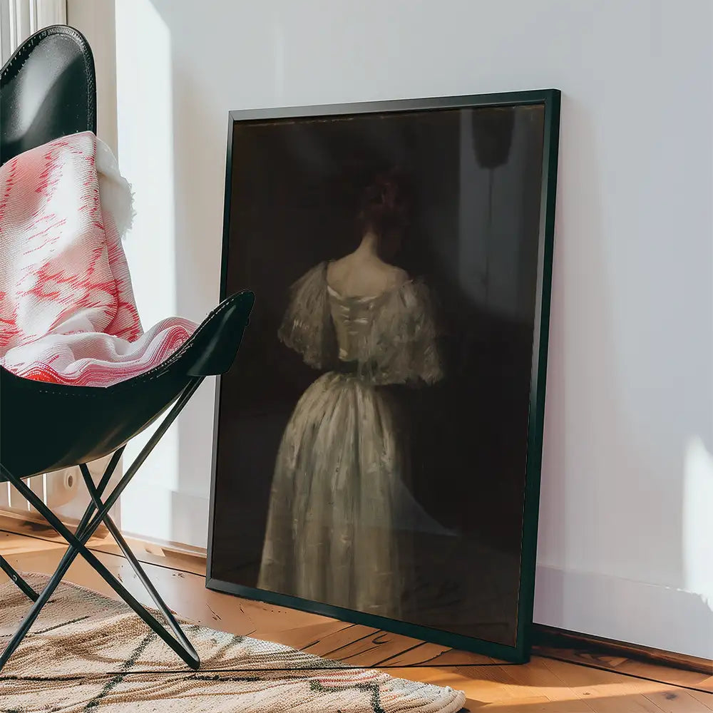 Framed painting of a woman in a white dress viewed from behind, leaning against a wall with a black chair and patterned rug nearby.
