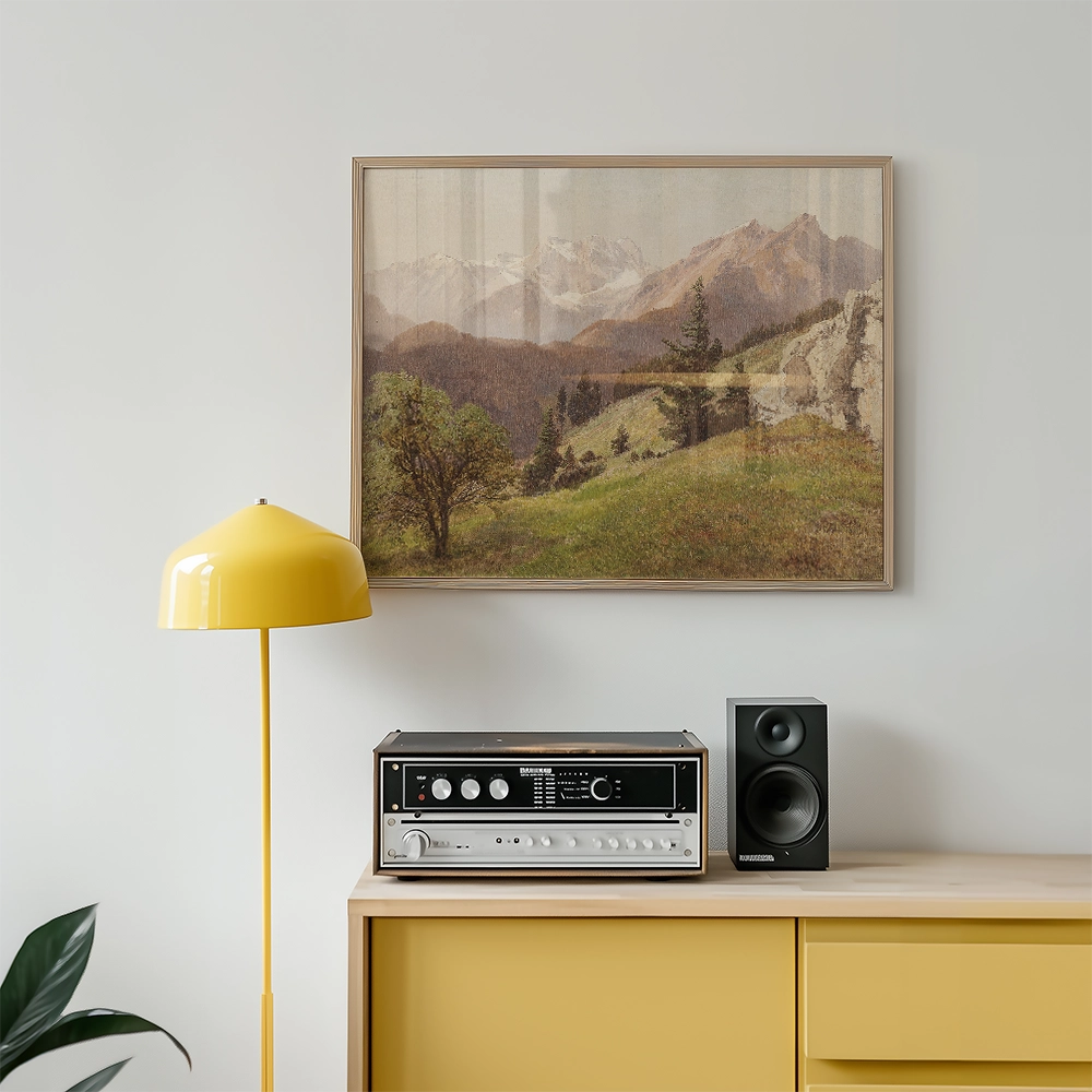 Painting of a scenic landscape with mountains and trees, framed and displayed above a vintage stereo and a yellow lamp in a modern interior setting.