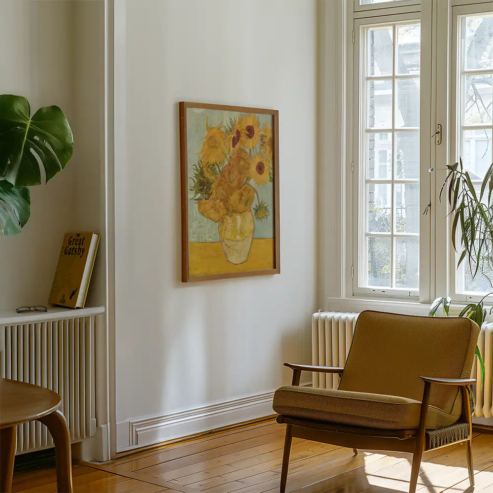Painting of sunflowers in a vase framed on a wall in a modern living room setting with a plant and a chair.