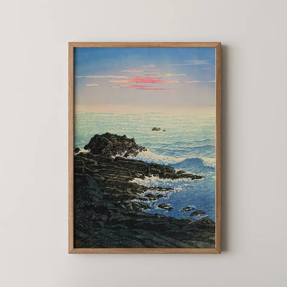 Framed painting of a serene ocean landscape with rocks, gentle waves, and a colorful sunset in the background.