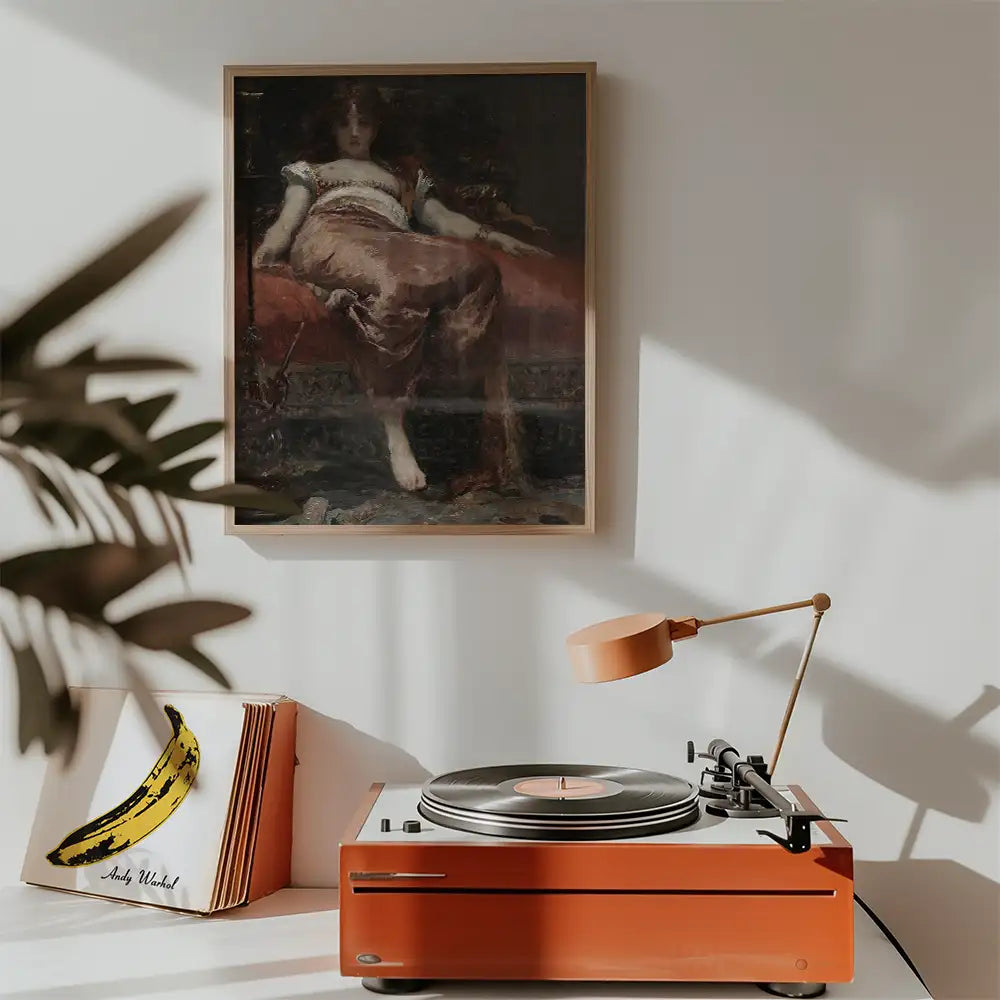 Painting of a woman reclining on a couch, framed and displayed above a vintage record player and a stack of albums, featuring a banana artwork.