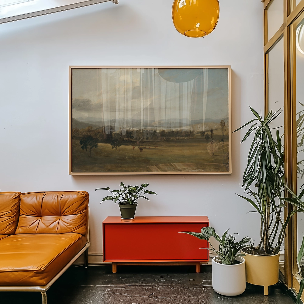 A landscape painting in a light wooden frame displayed on a wall above an orange sofa, next to a red cabinet and indoor plants.