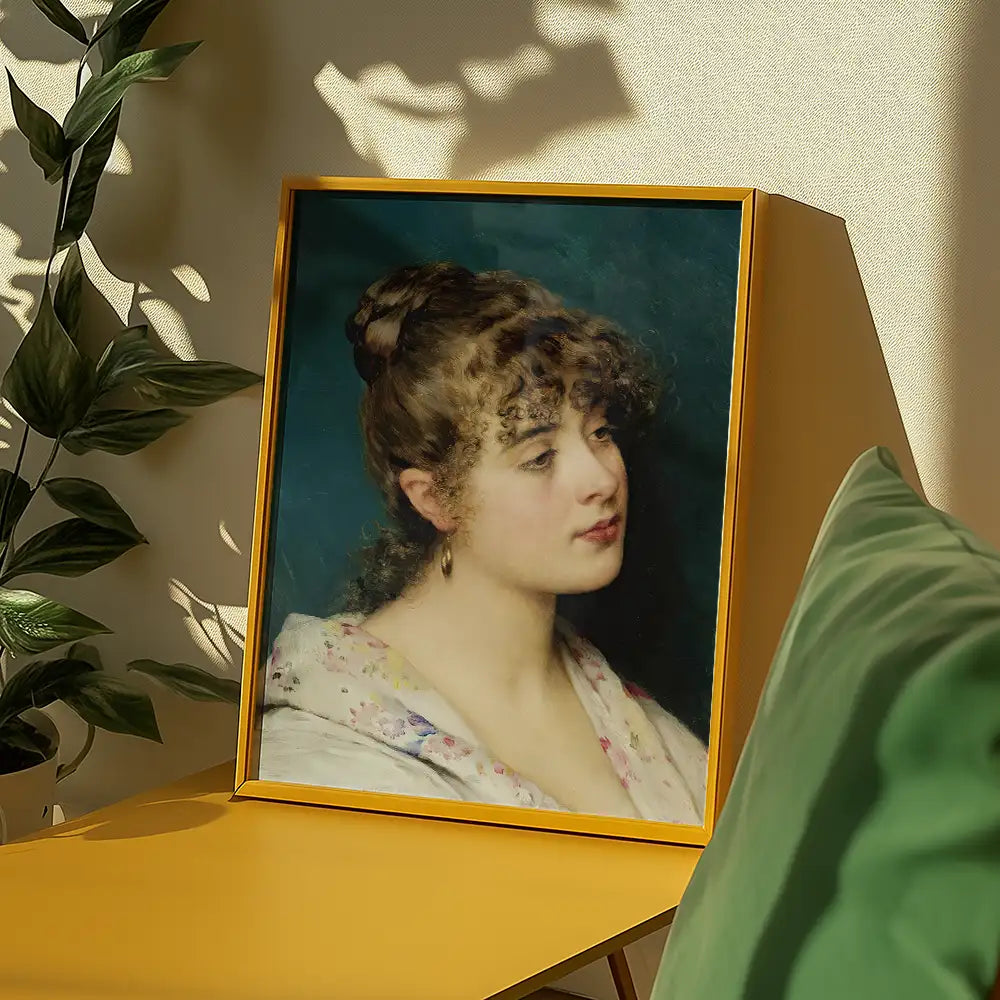 Framed painting of a young woman with curly hair, displayed on a yellow table with green cushions and indoor plants in the background.