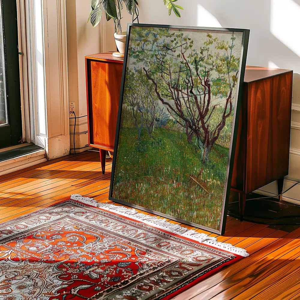 Framed painting of blossoming trees on a grassy field, displayed in a well-lit interior with wooden flooring and a decorative rug.