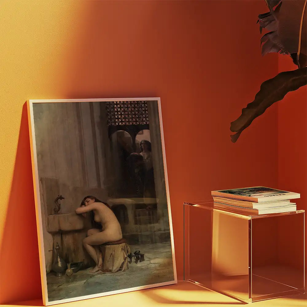 Framed painting of a nude woman sitting on a stool by a fountain, against a vibrant orange wall with books on a clear table.