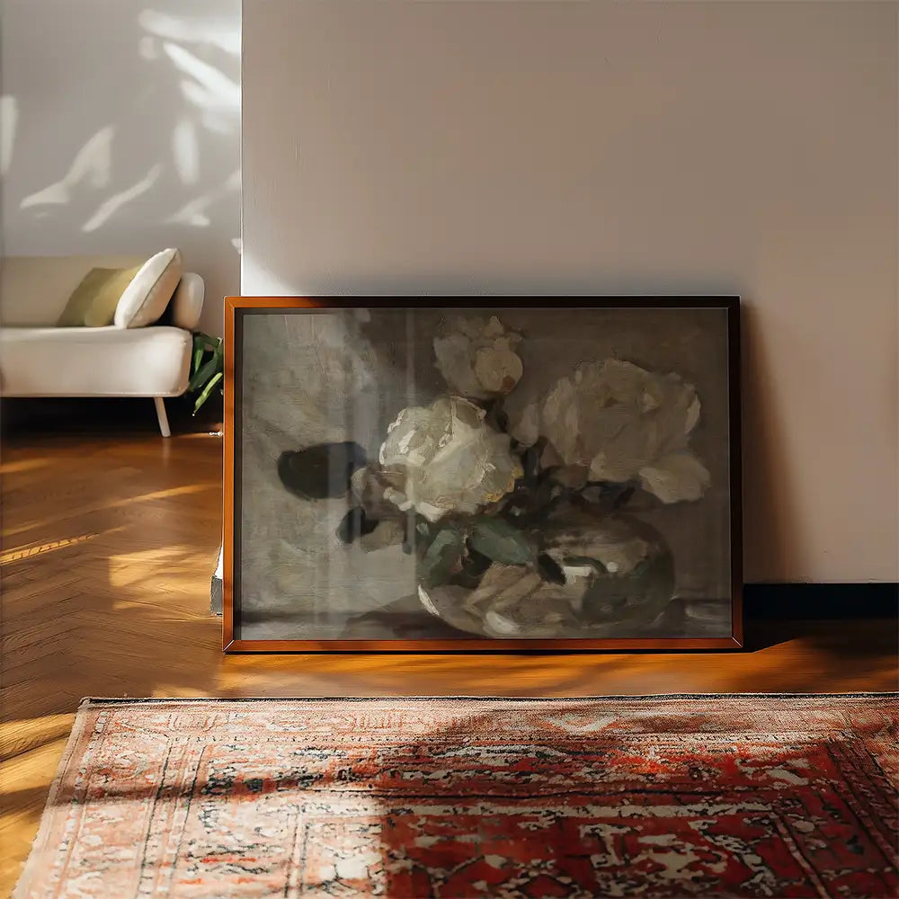 Framed painting of white flowers in a vase displayed on a wooden floor near a rug and a soft couch.