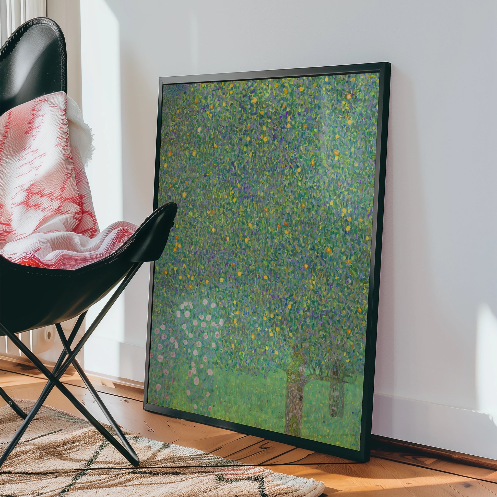 Framed colorful painting leaning against a wall next to a black chair and a patterned rug.