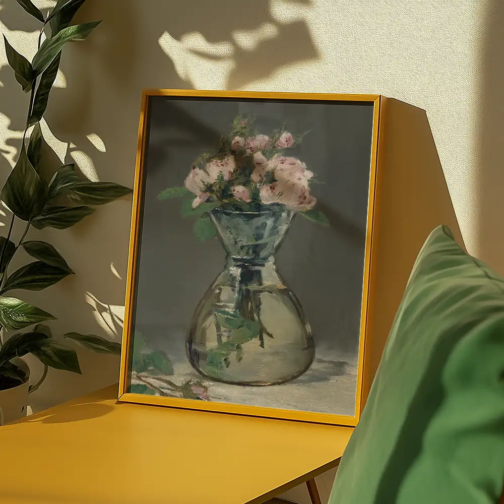 Framed painting of a bouquet of pink flowers in a glass vase, displayed on a yellow table with green decorative elements.
