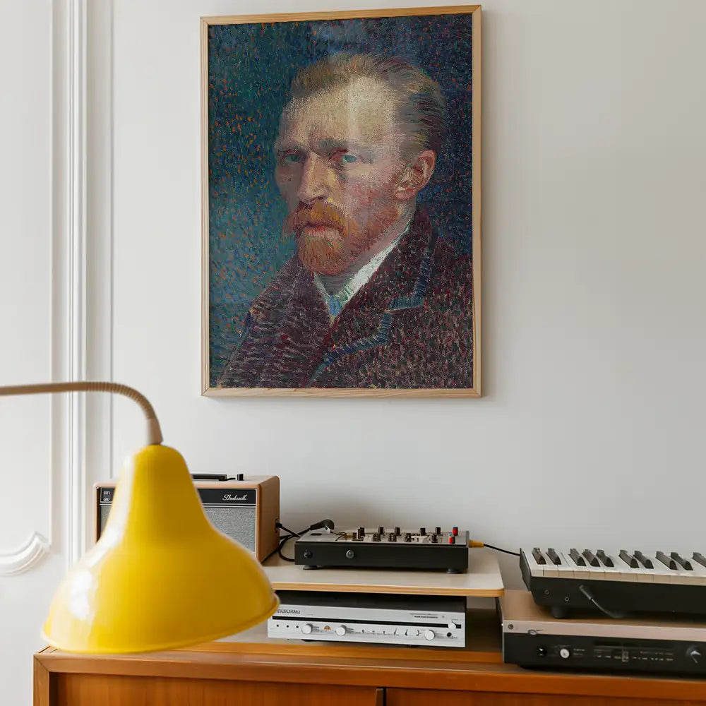 Framed painting of a male figure with a red beard and blue background, displayed on a wall above a record player and a yellow lamp.