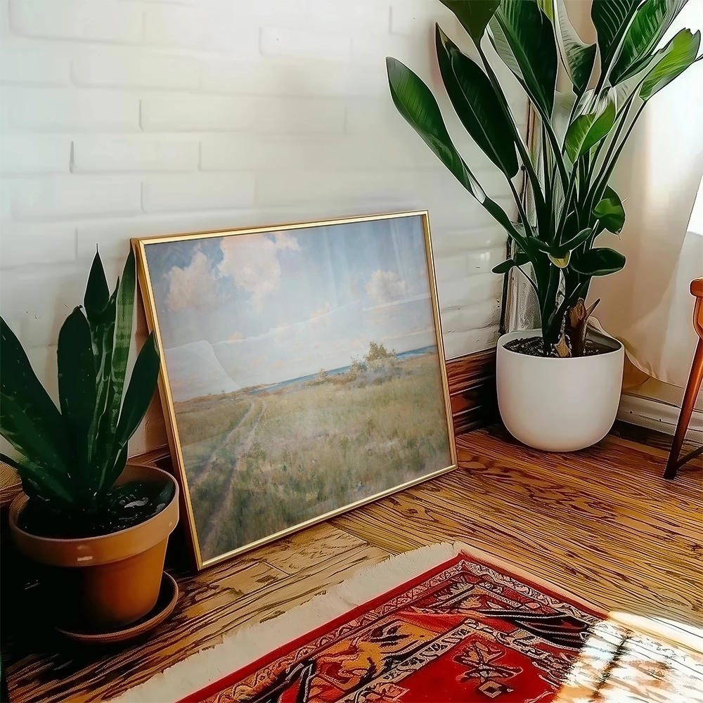 Framed landscape painting leaning against a wall with indoor plants and a colorful rug in a cozy setting.