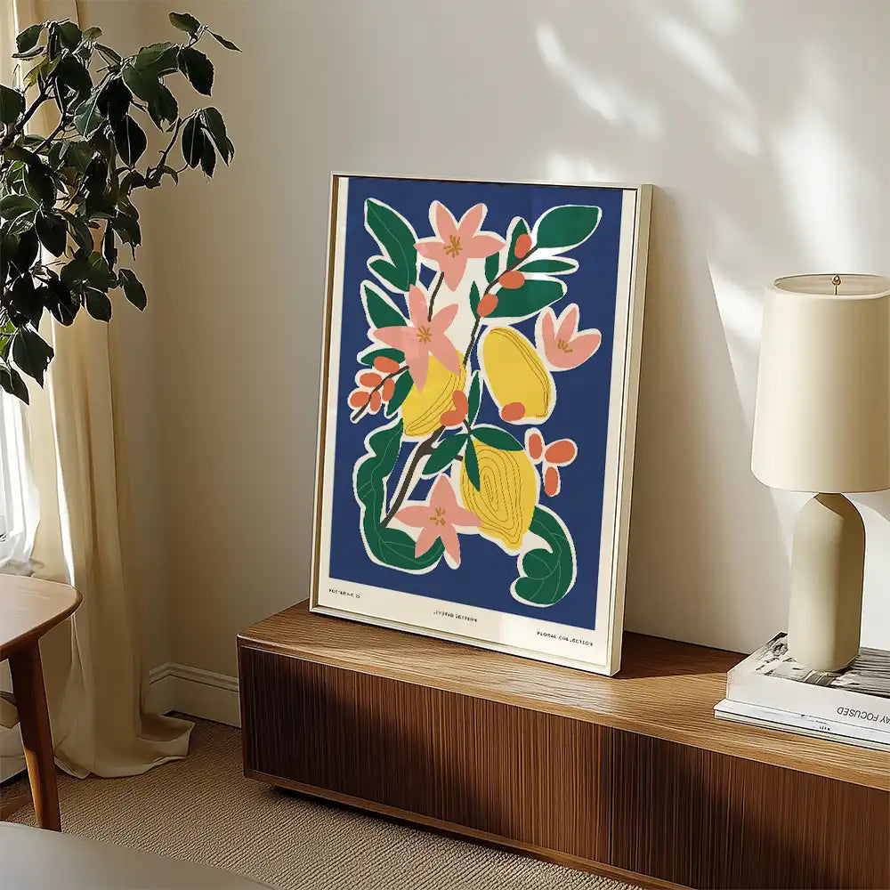Modern floral art poster featuring vibrant yellow lemons and pink flowers against a dark blue background, displayed in a stylish interior setting.