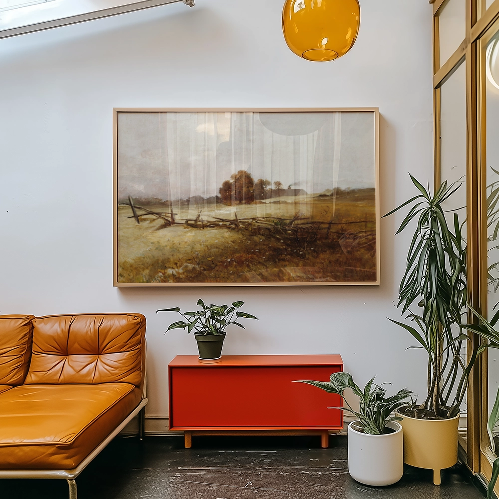 Framed landscape painting hanging on a wall above a red cabinet, paired with a brown leather sofa and indoor plants in pots.