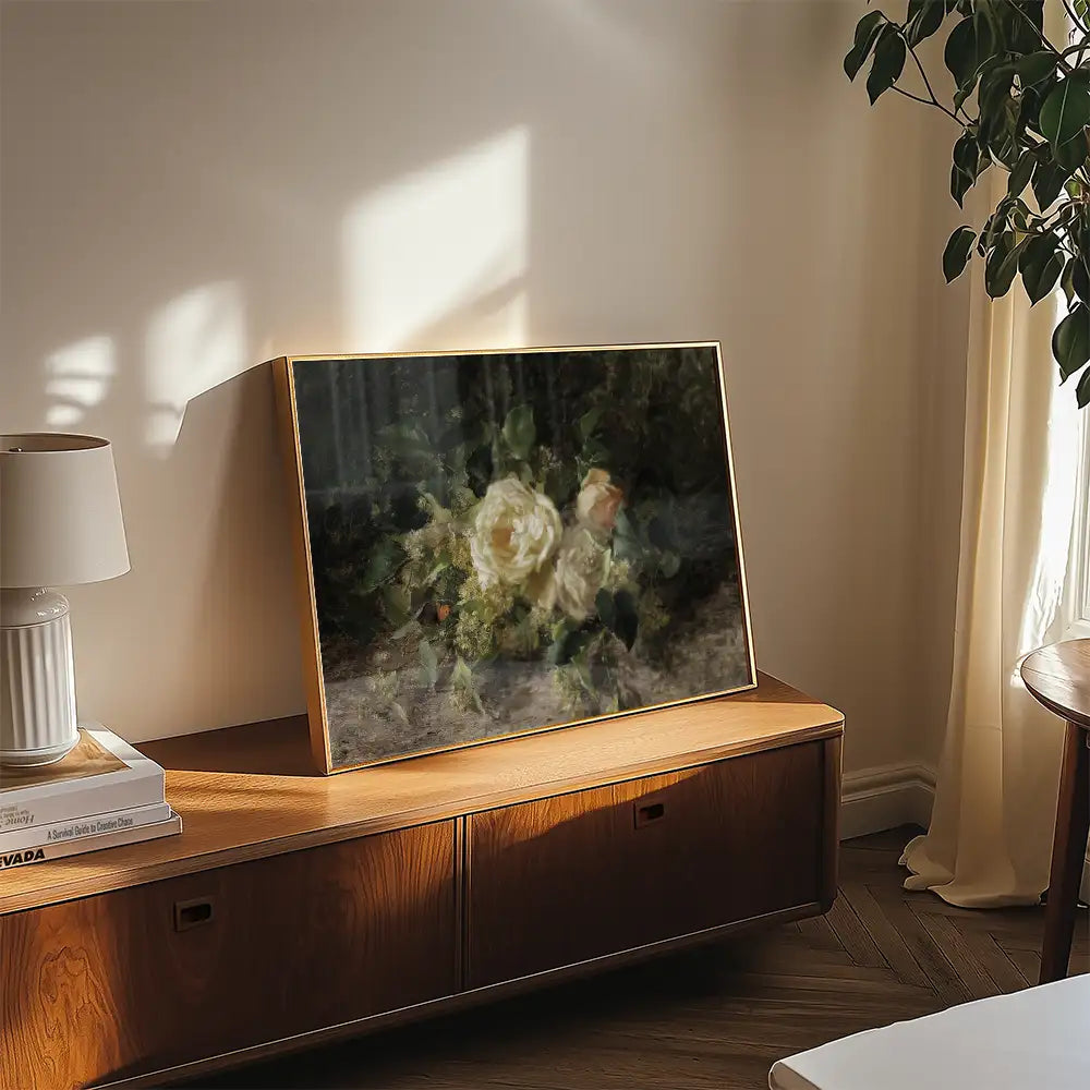 Painting of roses in a modern frame displayed on a wooden console table in a softly lit room.