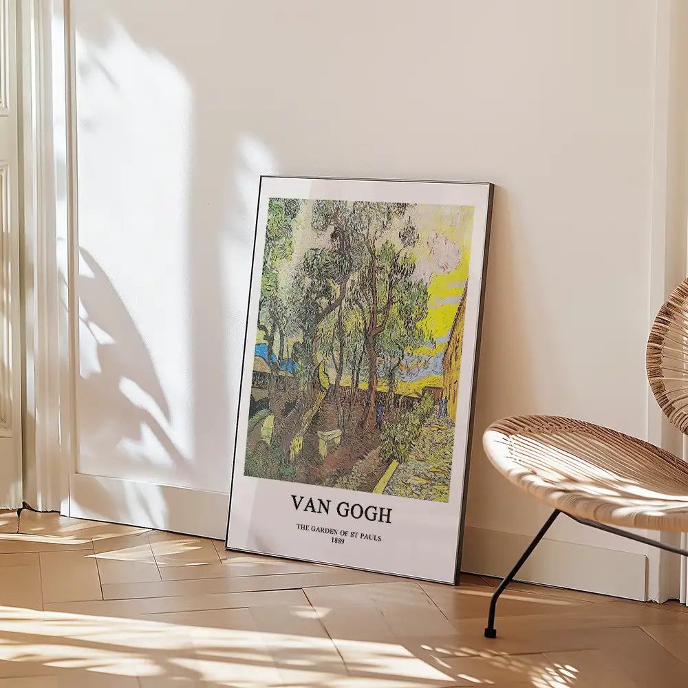 Framed poster of Vincent van Gogh's painting "The Garden of St Pauls" leaning against a wall in a bright room with a wicker chair.
