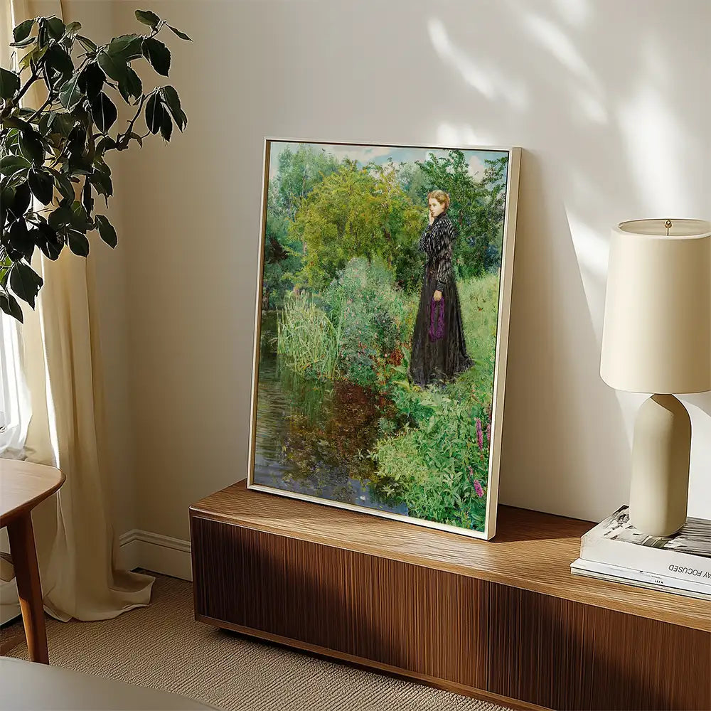 Framed painting of a woman in a black dress standing near a lush green landscape and a pond, displayed in a modern living room setting.