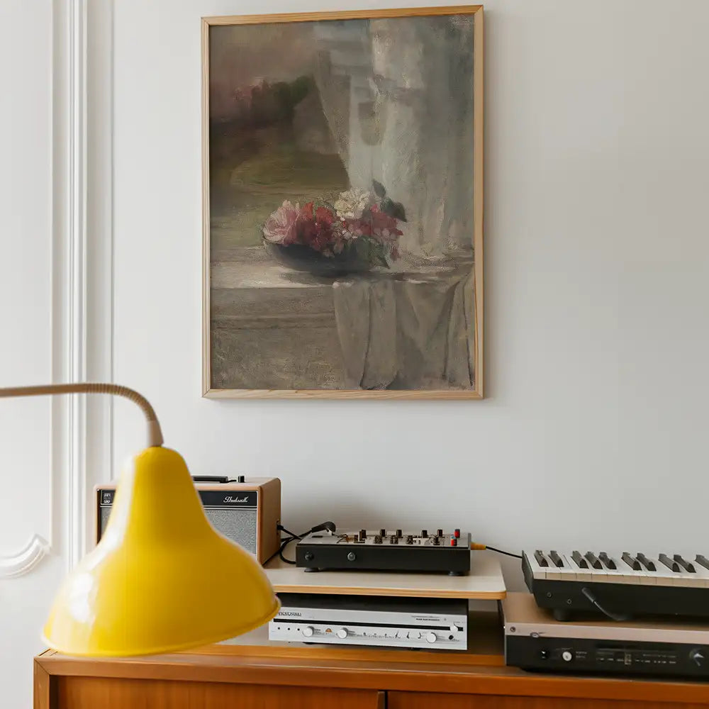 Framed painting of a bouquet of flowers on a table, displayed on a wall above a vintage audio setup and yellow lamp.