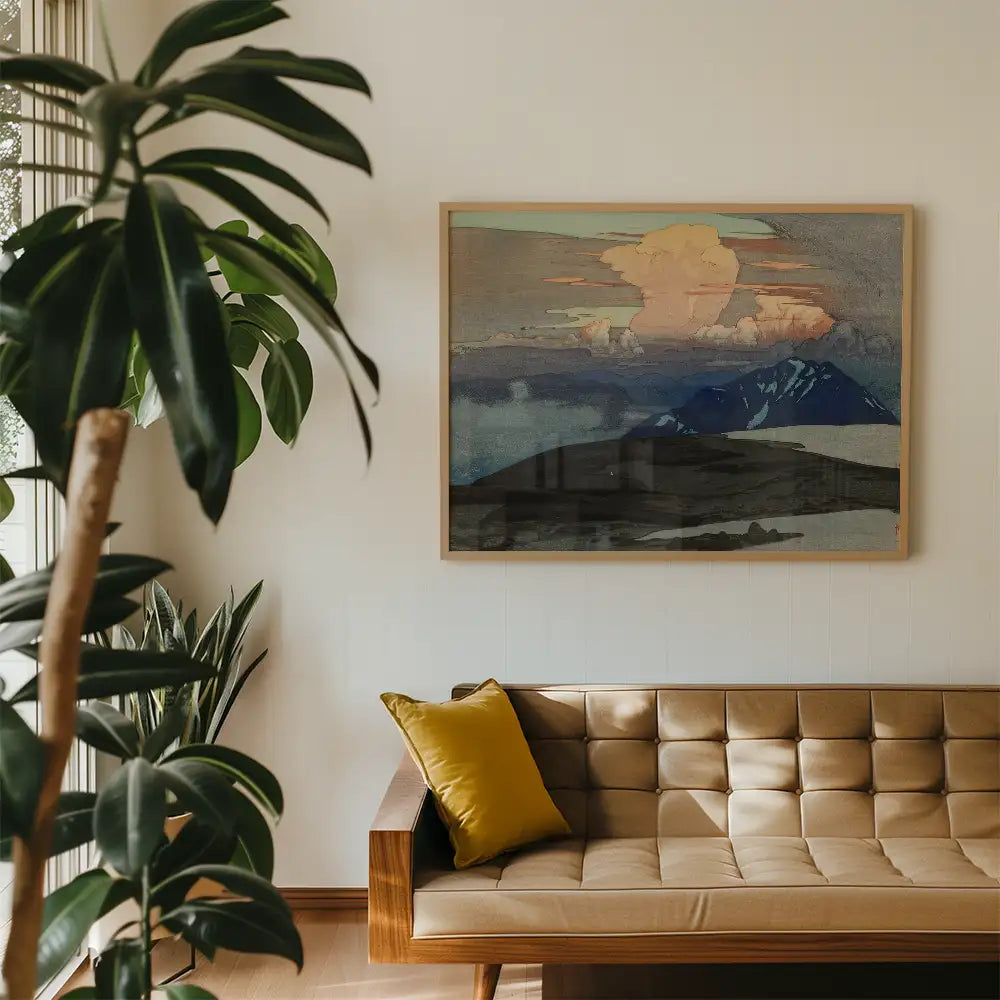 Framed landscape painting of mountains and clouds displayed above a modern sofa with a yellow cushion and indoor plants.