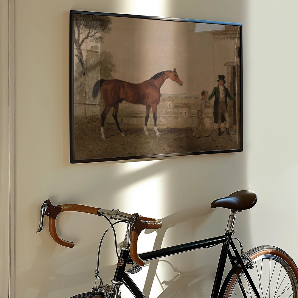 Painting of a brown horse standing next to a boy and a man in formal attire, framed and displayed on a wall beside a vintage bicycle.