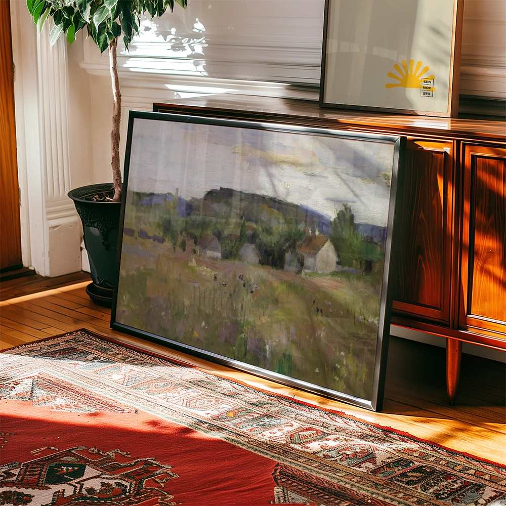Framed painting of a serene landscape featuring rolling hills and small houses, placed beside a plant on a wooden floor rug.