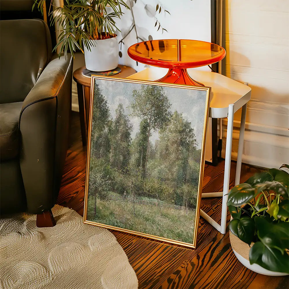 Framed landscape painting featuring trees, displayed in a cozy living room setting with a plant and modern furniture.