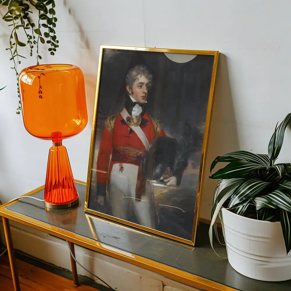 Framed painting of a military officer in colorful uniform displayed on a table with an orange lamp and a potted plant.