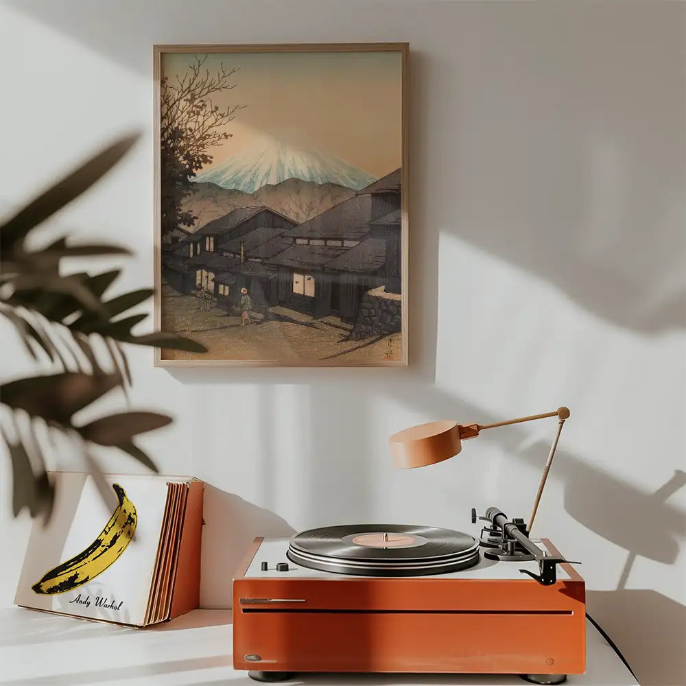 Painted artwork of a serene landscape featuring traditional houses and mountains, displayed above a retro turntable with an orange base and a record, complemented by a banana-themed album cover.