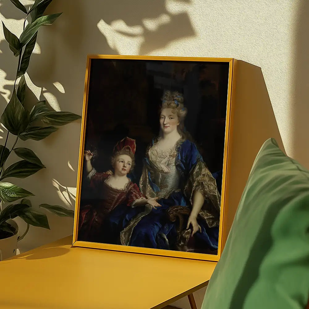 Painting of a woman in blue and gold attire with a child beside her, framed in a yellow border, displayed on a table with plants in a well-lit room.