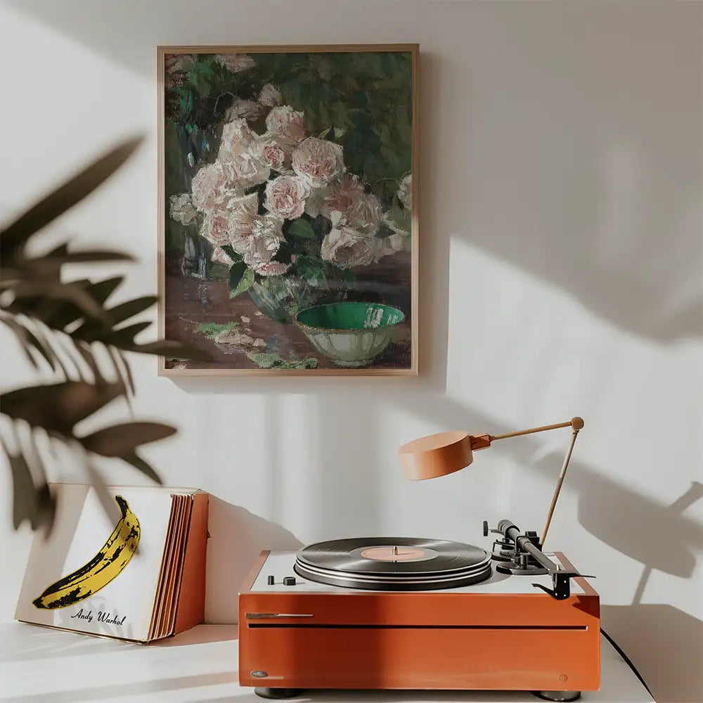 Painting of white roses in a vase, displayed above a vintage record player and a green bowl, in a cozy indoor setting.