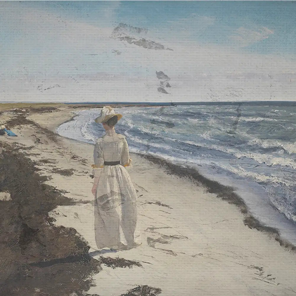 A woman in a light dress and hat walking along a sandy beach with waves lapping at the shore under a blue sky.