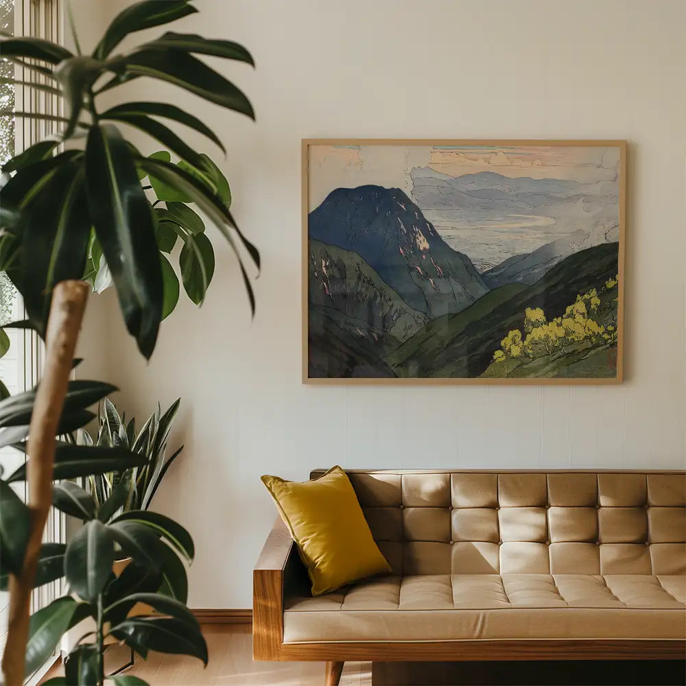 Framed landscape painting of mountains above a sofa in a minimalist living room with green plants.