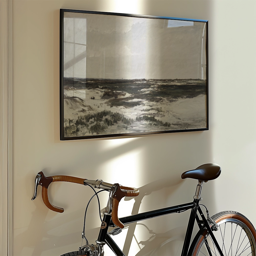 A framed landscape painting hanging on a wall next to a black bicycle with brown leather accents.