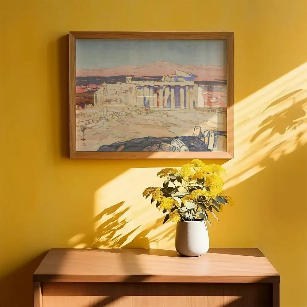 Framed painting of ancient architecture displayed on a yellow wall with a vase of yellow flowers on a wooden table.