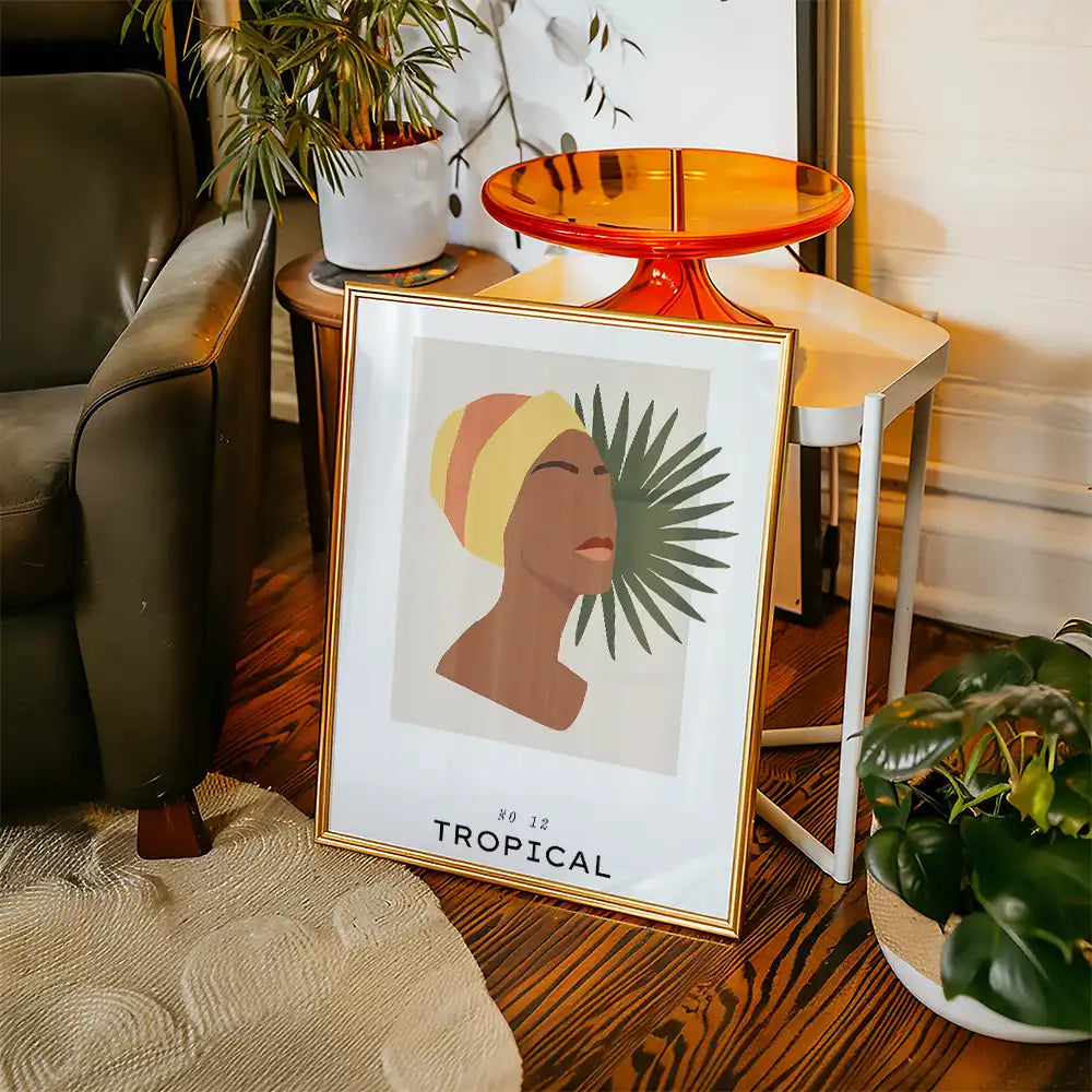 Modern wall art print featuring a silhouette of a woman with a yellow headwrap and tropical leaves, framed in gold, perfect for home decor.