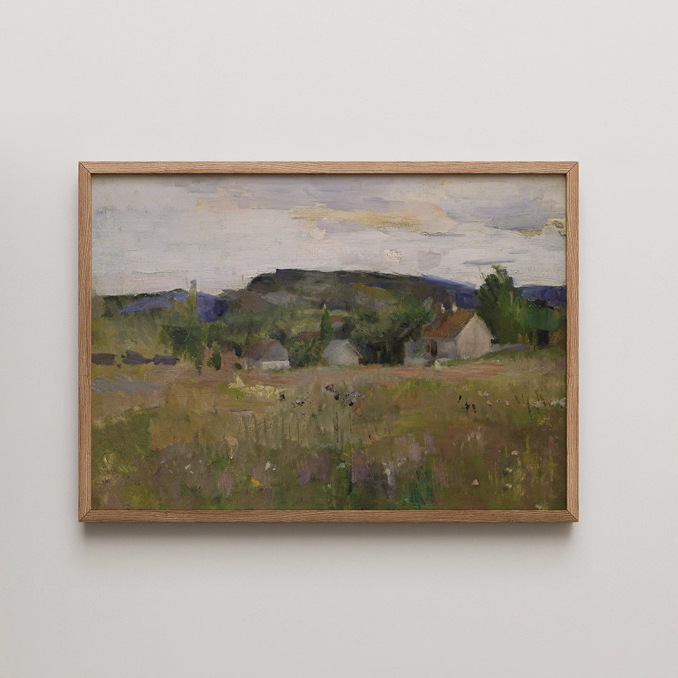 Landscape painting featuring a rural scene with softly colored hills and small white houses under a cloudy sky, framed in light wood.
