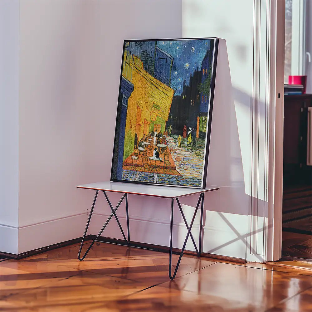 Painting of a vibrant night scene with a café, featuring yellow and blue tones, displayed on a modern table in a cozy interior setting.