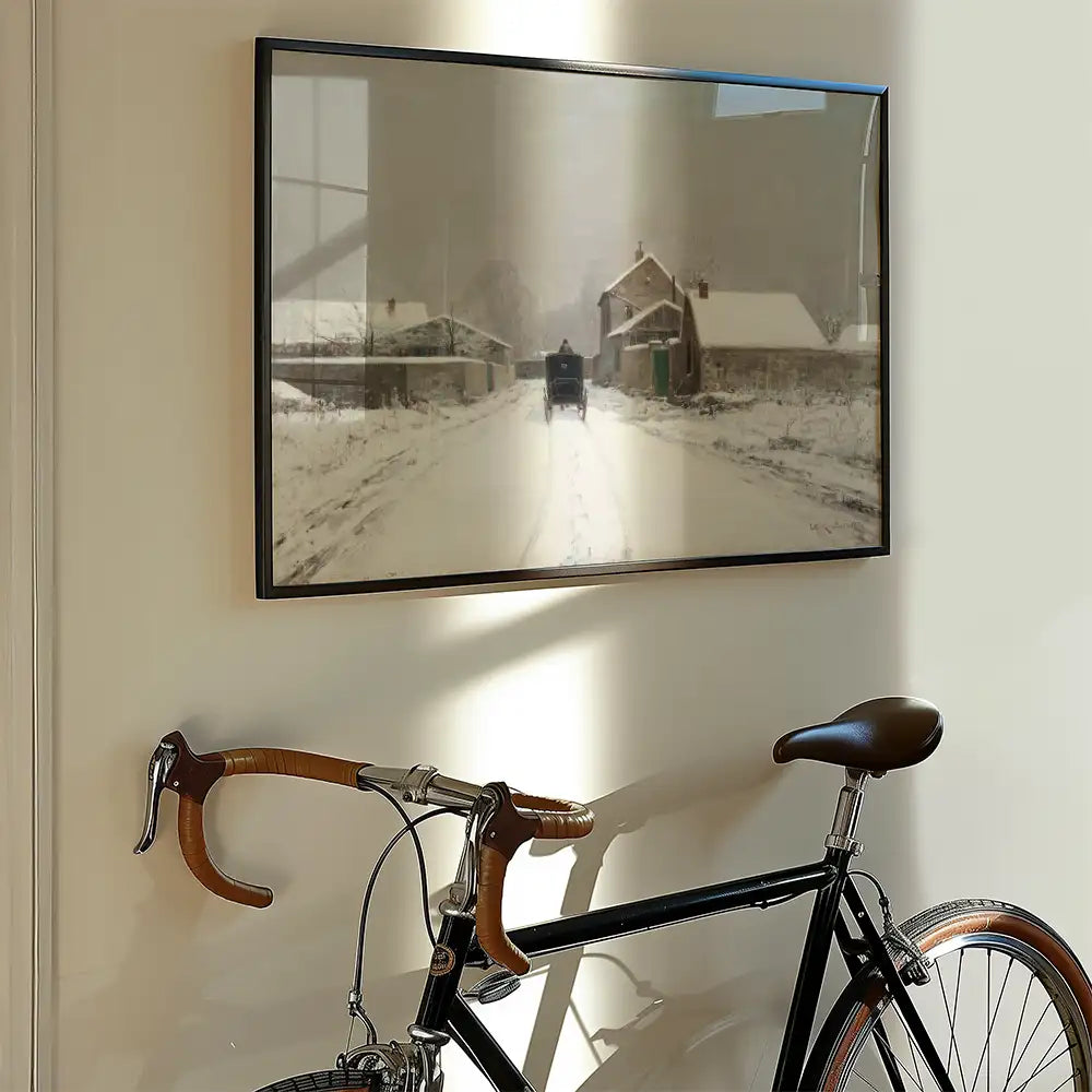 Framed painting of a snowy road with a horse-drawn carriage, displayed on a wall above a bicycle.
