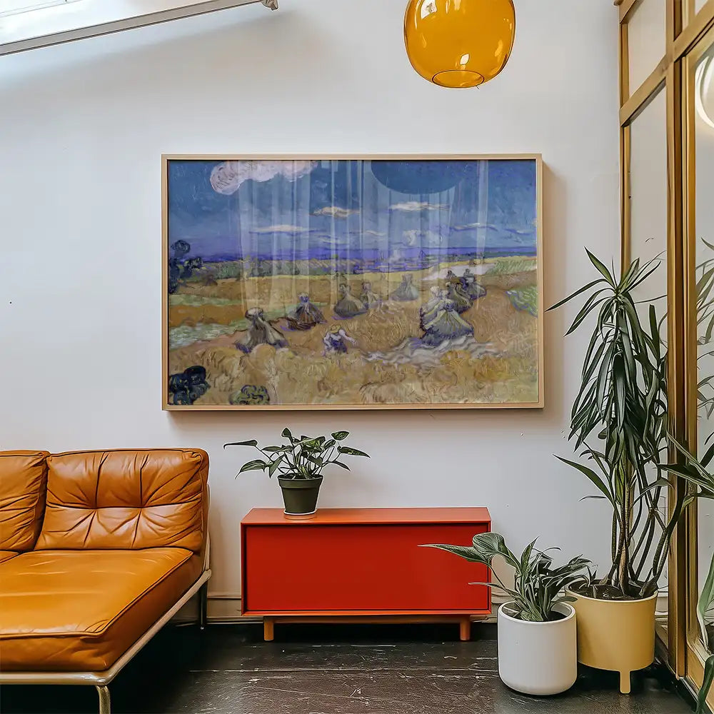 Framed painting of a landscape with figures working in a field, displayed on a wall above a stylish orange couch and a red cabinet, surrounded by indoor plants.
