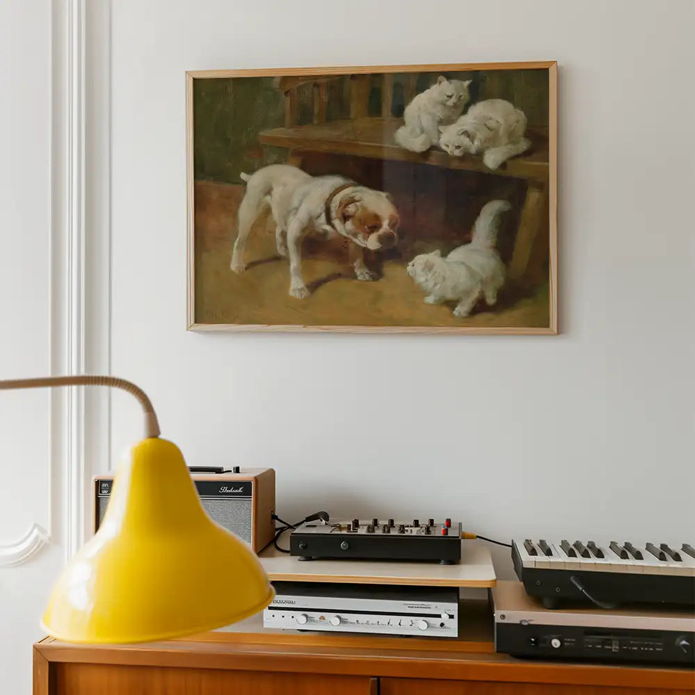 Painting of a dog interacting with three white kittens, framed and hanging on a wall in a cozy living space with a yellow lamp and vintage audio equipment.