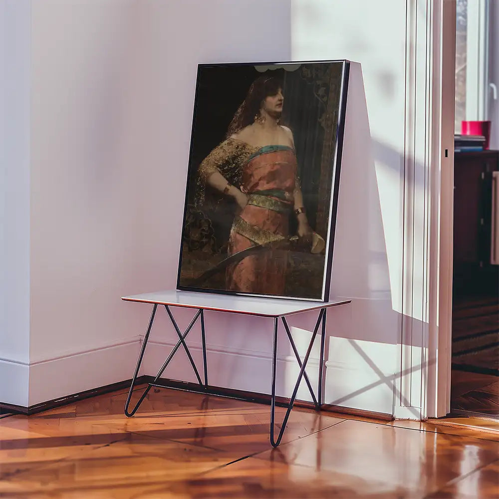 Framed painting of a woman in a pink dress with a sword displayed on a small white table in a bright room.