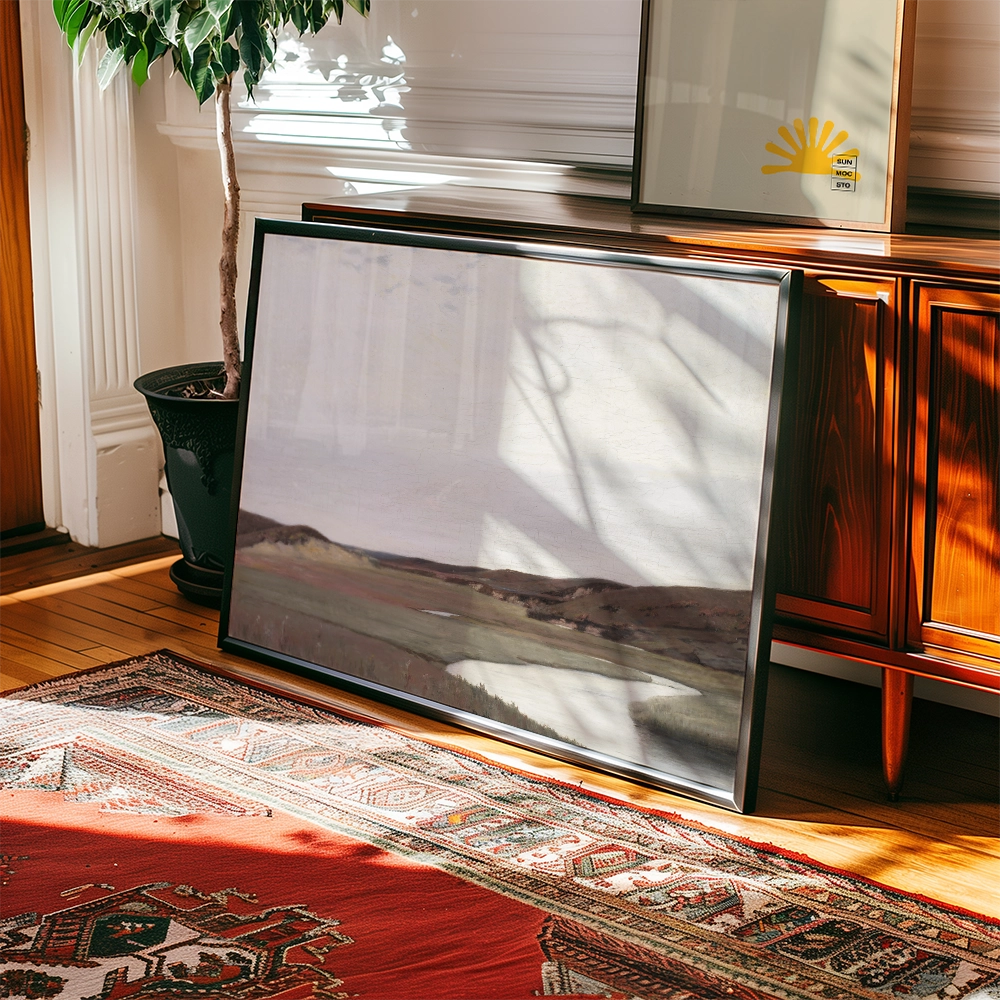 Framed landscape painting resting against a wooden cabinet in a sunlit room, with a decorative rug and a potted plant nearby.