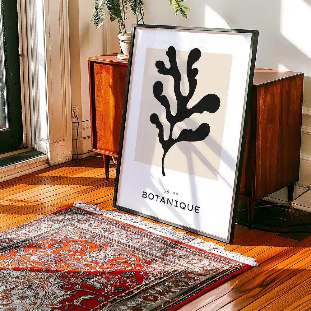 Modern botanical art print featuring a black abstract leaf design and minimalist typography, displayed in a stylish interior setting.