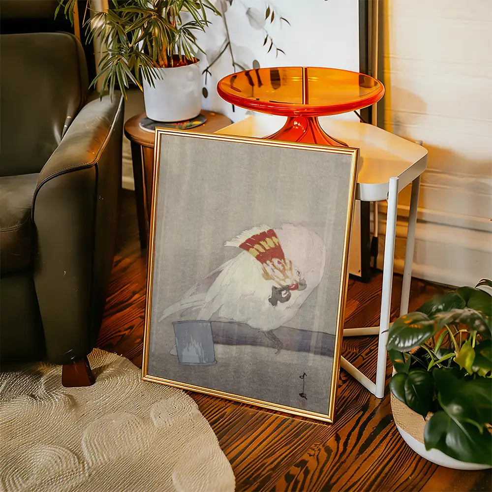 Framed painting of a white bird with colorful details, displayed in a cozy living space with a plant and modern furniture.