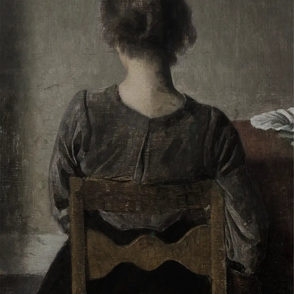 A woman seated with her back facing the viewer, wearing a simple dark blouse, in a muted and atmospheric setting.