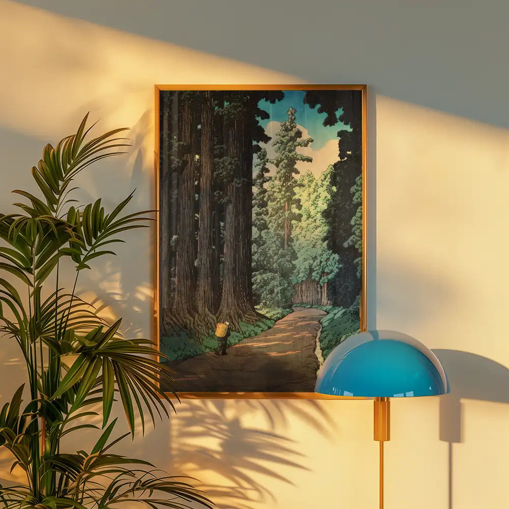 Framed painting of a serene forest landscape featuring tall trees and a winding path, with decorative plant and modern lamp in the foreground.
