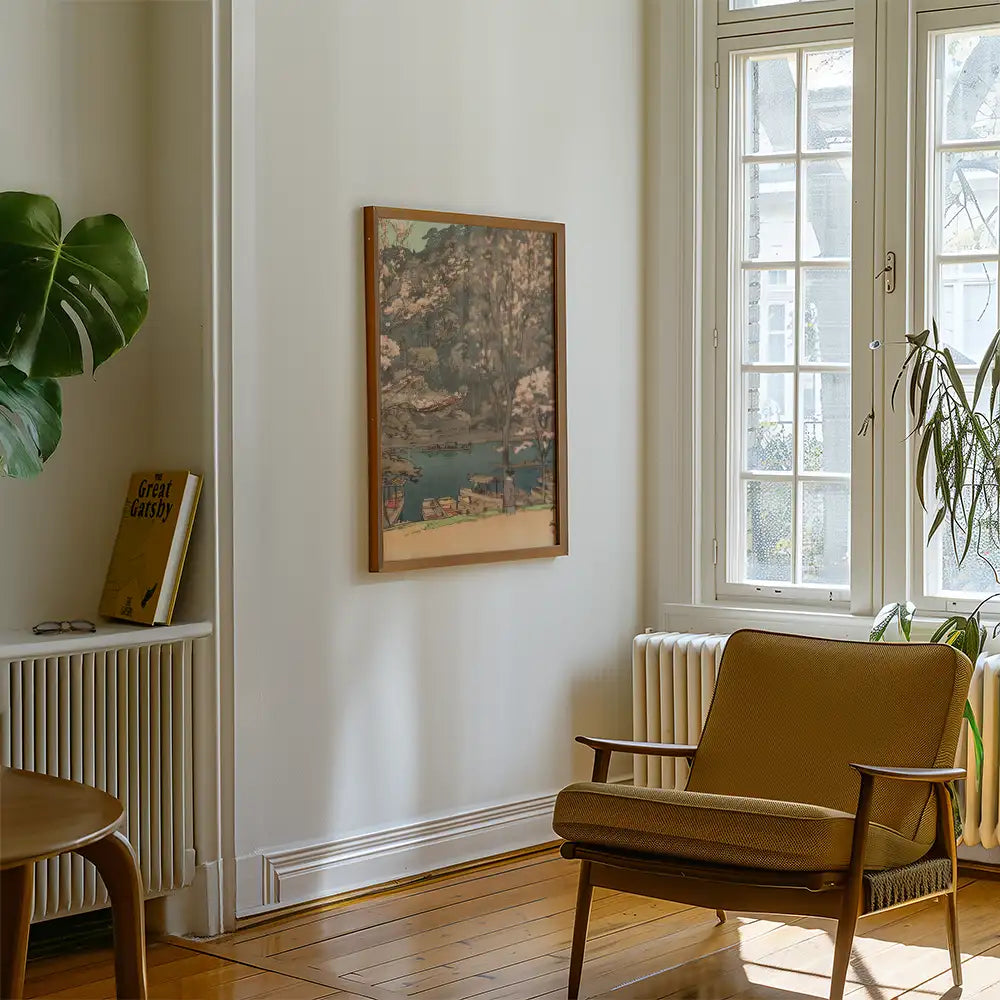 A framed painting of a serene landscape hanging on a wall next to a modern armchair and a potted plant in a stylish living room setting.