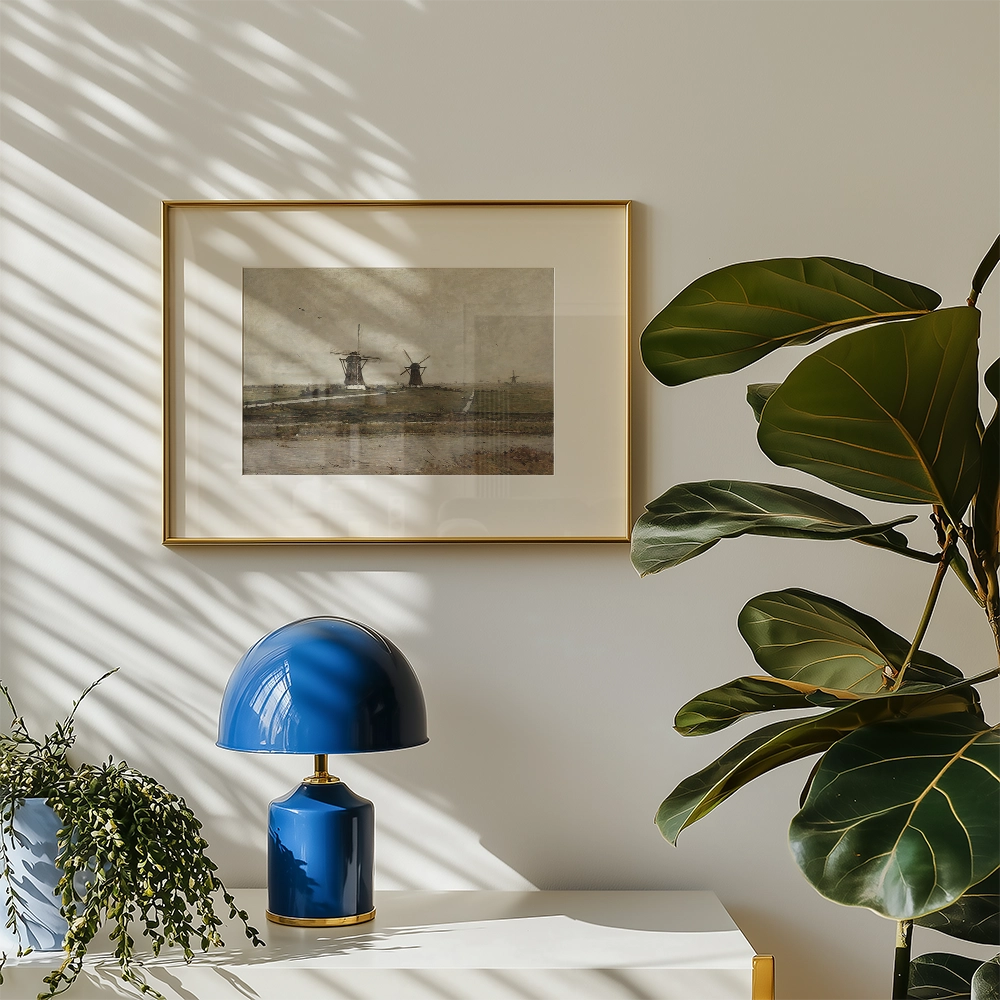Framed painting of windmills on a landscape wall with a blue lamp and indoor plant in a modern setting.